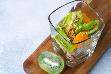 Glass with fruit pieces and oatmeal muesli on wooden board