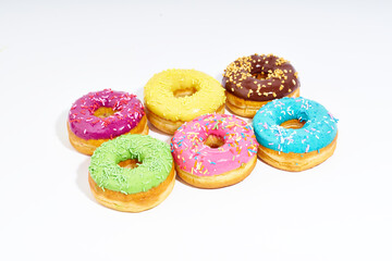 Sweet colorful glazed doughnuts from above on white background. Junk food top view, sugar treat