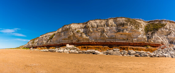 A panorama view eastward along the white, red and orange stratified chalk cliffs of Old Hunstanton, Norfolk, UK