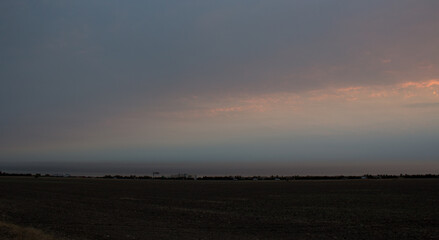 Rainbow sunrise in the clouds over a field