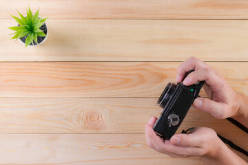 Man holding vintage camera on wooden background with copy space. World photography day concept.