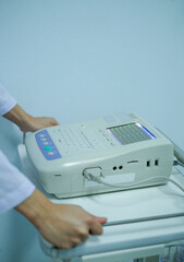 Doctor push of electrocardiography machine in the hospital