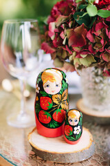 Russian traditional wooden toy - matryoshka, matryoshka in the form of a girl in a national costume. Souvenir. Table setting in Russian style.