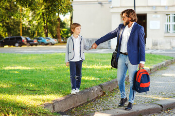 Father and son go hand in hand to school. Beginning of lessons. Back to school.