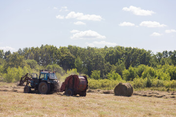 tractor in field throwing out hay roll