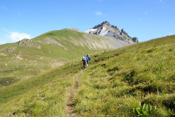 Fototapeta na wymiar Two trekkers walking along a mountain path in Roburent, Piedmont (Italy)