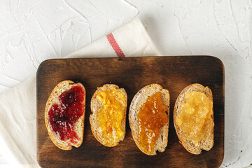 Slice of bread covered with fruit jam on wooden board