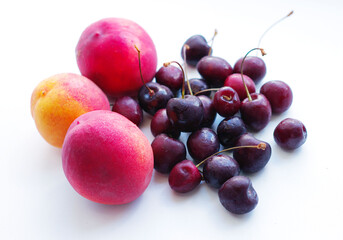 three peaches, nectarine and a handful of sweet cherries lie on a white background. Isolate, a natural dessert made from berries. A tasty, healthy snack, a piece of summer, a harvest. Fruit on a white