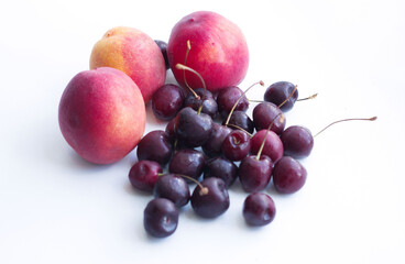 three peaches, nectarine and a handful of sweet cherries lie on a white background. Isolate, a natural dessert made from berries. A tasty, healthy snack, a piece of summer, a harvest. Fruit on a white