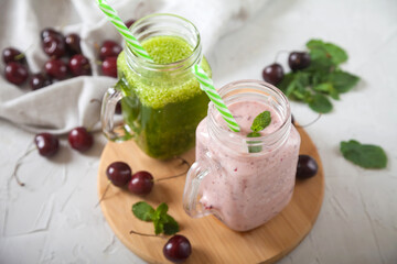 Fresh greens and sweet cherry smoothies, sweet cherry berries and linen napkin on a concrete background. Top view.