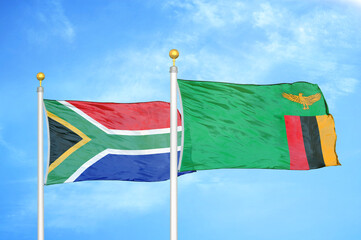 South Africa and Zambia two flags on flagpoles and blue sky