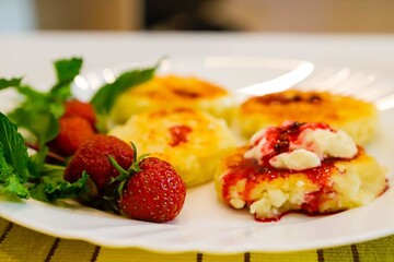 on a yellow napkin is a plate with cheesecakes, strawberries and mint