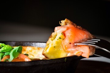 fried eggs with smoked salmon in a pan and a piece on a fork