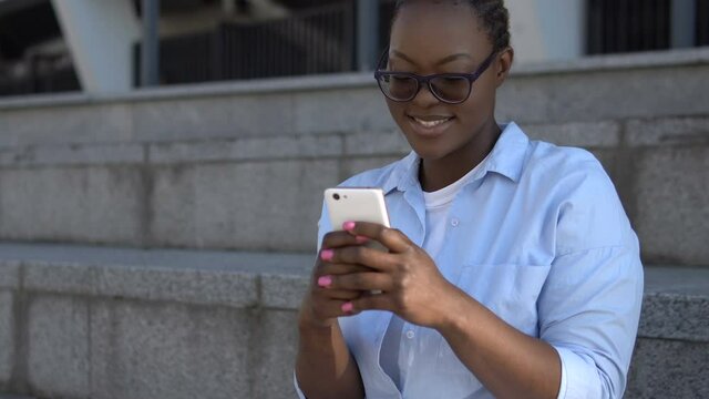 Afro-american female using mobile app on smartphone smile on face, communication
