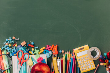 top view of apple, calculator and school supplies on green chalkboard © LIGHTFIELD STUDIOS
