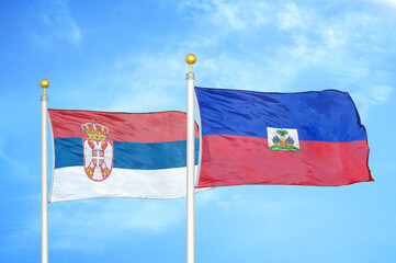 Serbia and Haiti two flags on flagpoles and blue sky