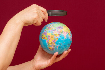 image of a hand holding a magnifying glass over an world globe