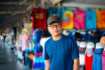 Young Korean man wearing  green military hat against  blurred clothing store background.