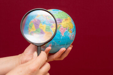 image of a hand holding a magnifying glass over an world globe
