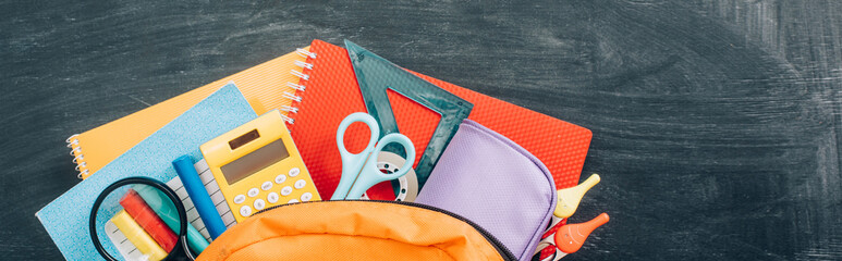 top view of school backpack with stationery on black chalkboard, panoramic shot © LIGHTFIELD STUDIOS