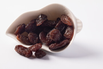 Black currant in a white ceramic cup on a white background