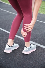 Girl in the stadium. Legs of the girl close-up foot injury. Woman suffering from leg pain after exercise