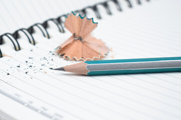 Light blue color wood pencil crayon placed in front of a white note paper diary