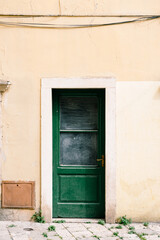Green doors with shabby dirty windows against the white wall