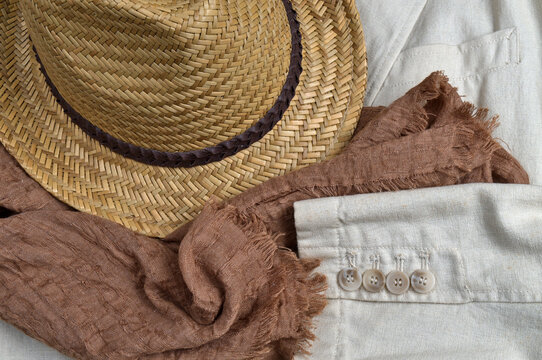 Straw hat, brown scarf and classic linen coat. Stylish summertime outfit theme