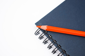 Orange color wood pencil crayon placed on a blue color note paper diary