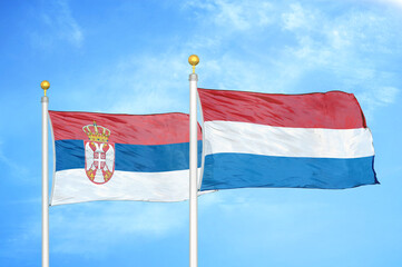 Serbia and Netherlands two flags on flagpoles and blue sky