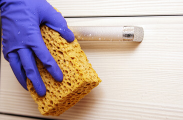 Hand in blue glove and sponge handle furniture water drops