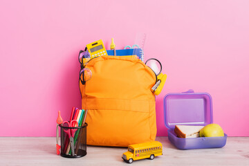 yellow backpack with school stationery near toy school bus, lunch box and pen holder with felt pens...
