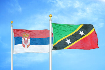 Serbia and Saint Kitts and Nevis two flags on flagpoles and blue sky