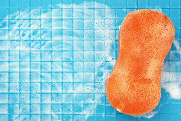 A large red sponge for cleaning on a blue surface with white foam cages