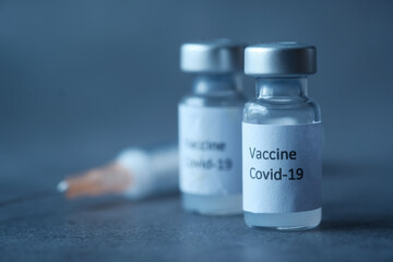 Close up of coronavirus vaccine and syringe on black background 