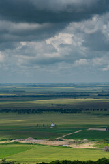 Fototapeta premium Aerial views Prairie landscapes of yellow and green fields under bold cloudy skies bright lighted areas