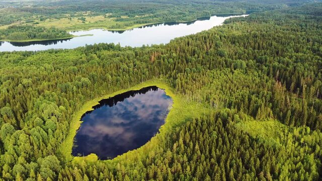 Aerial view of a round lake and a river in the middle of the forests of Valday, Russia