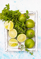 Composition with summer tropical fruits with lime, mint and aromatic herbs on pastel green background. Food concept.