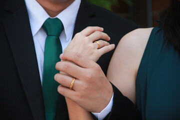 A man and a woman with wedding ring holding hands