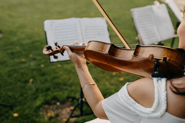 Woman playing violin outdoors, at a wedding, close-up.