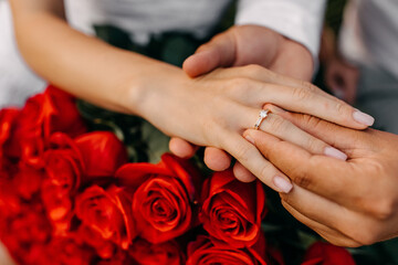 Close up of man putting a diamond engagement ring on woman's finger. Engagement concept.