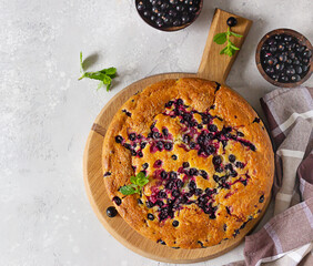 Sweet homemade cake or with cornmeal and black currant decorated with mint, selective focus. Light grey background. Summer baking.