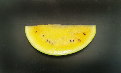 slice of yellow watermelon on a black background
