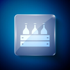 White Bottles of wine in a wooden box icon isolated on blue background. Wine bottles in a wooden crate icon. Square glass panels. Vector Illustration.