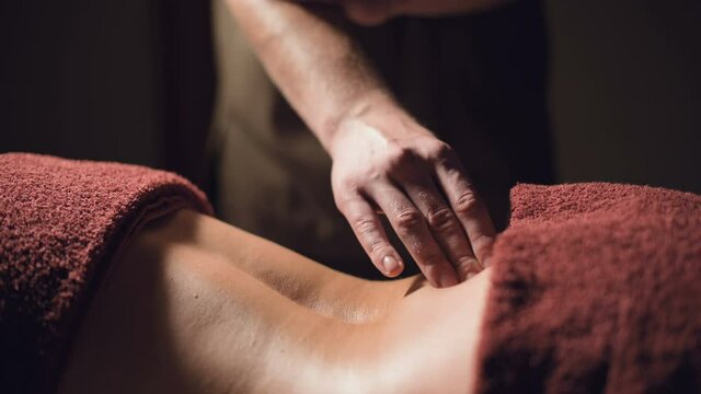 close-up Cosmetology and physiotherapy. Professional massage to the lower back of a woman is made by a masseur man. Concept of manul therapy and massage spa treatments