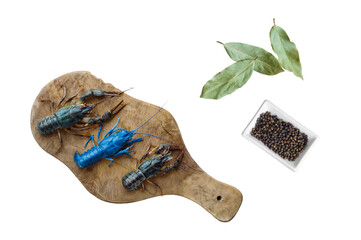 live crayfish on a kitchen board next to spices pepper and bay leaf
