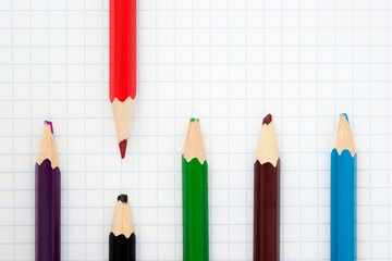  sharp red pencil and blunt colored pencils on a writing-book leaf