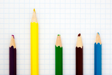  sharp  yellow pencil and blunt colored pencils on a writing-book leaf