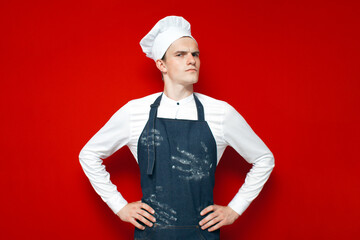 portrait of a serious chef on red isolated background, kitchen worker in uniform